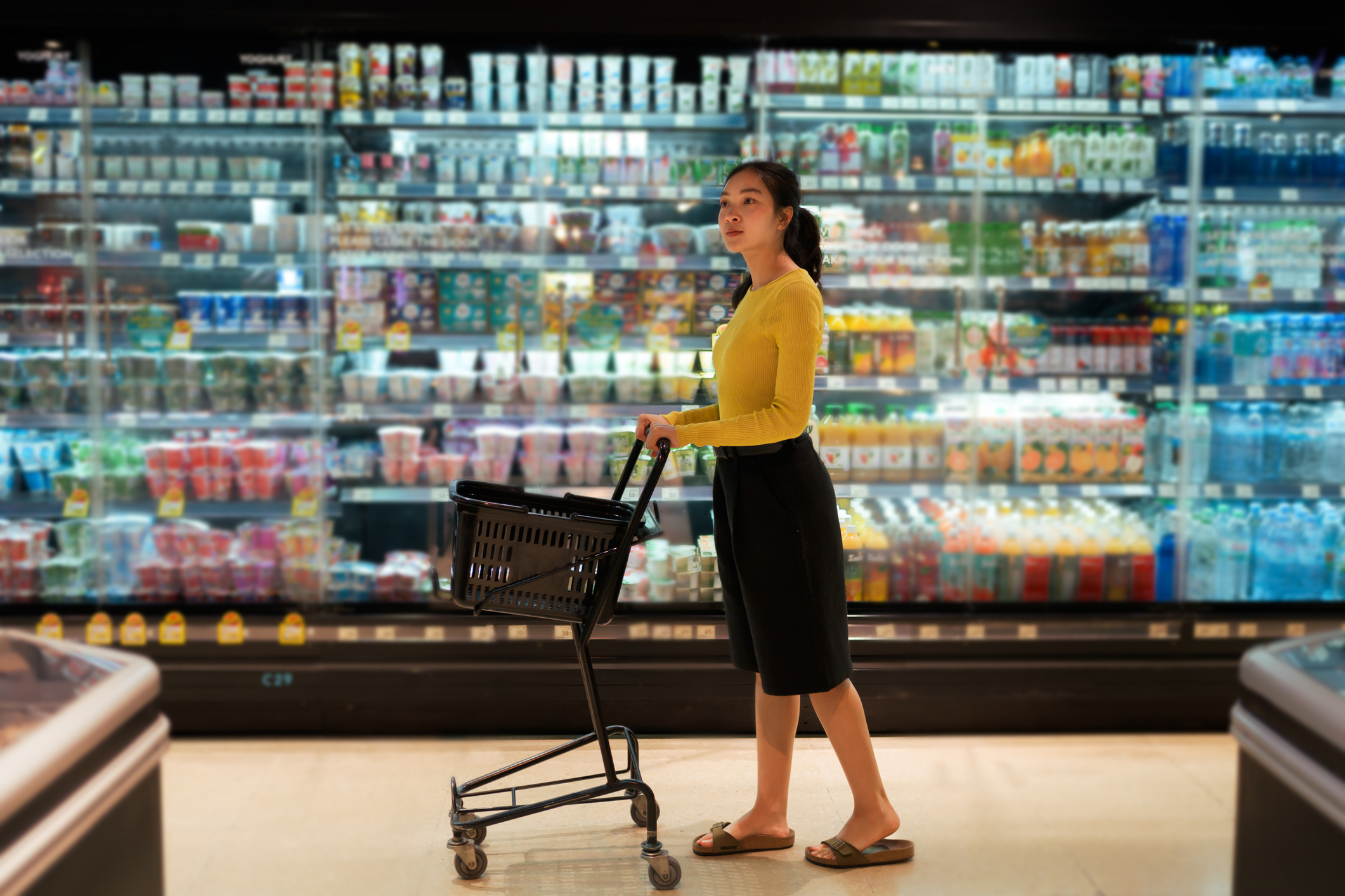 Woman pushing shopping cart in supermarket aisle